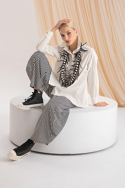 Model wearing a white shirt with embellished striped wide-leg trousers