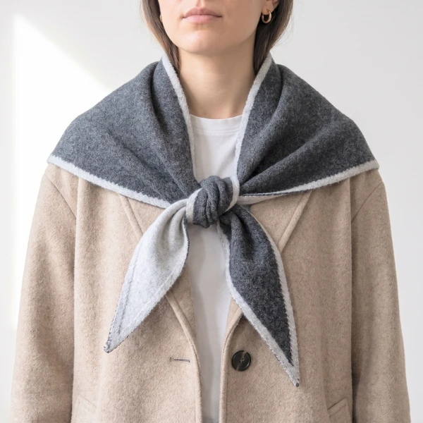 Dark grey triangle scarf with light grey trim styled over beige coat